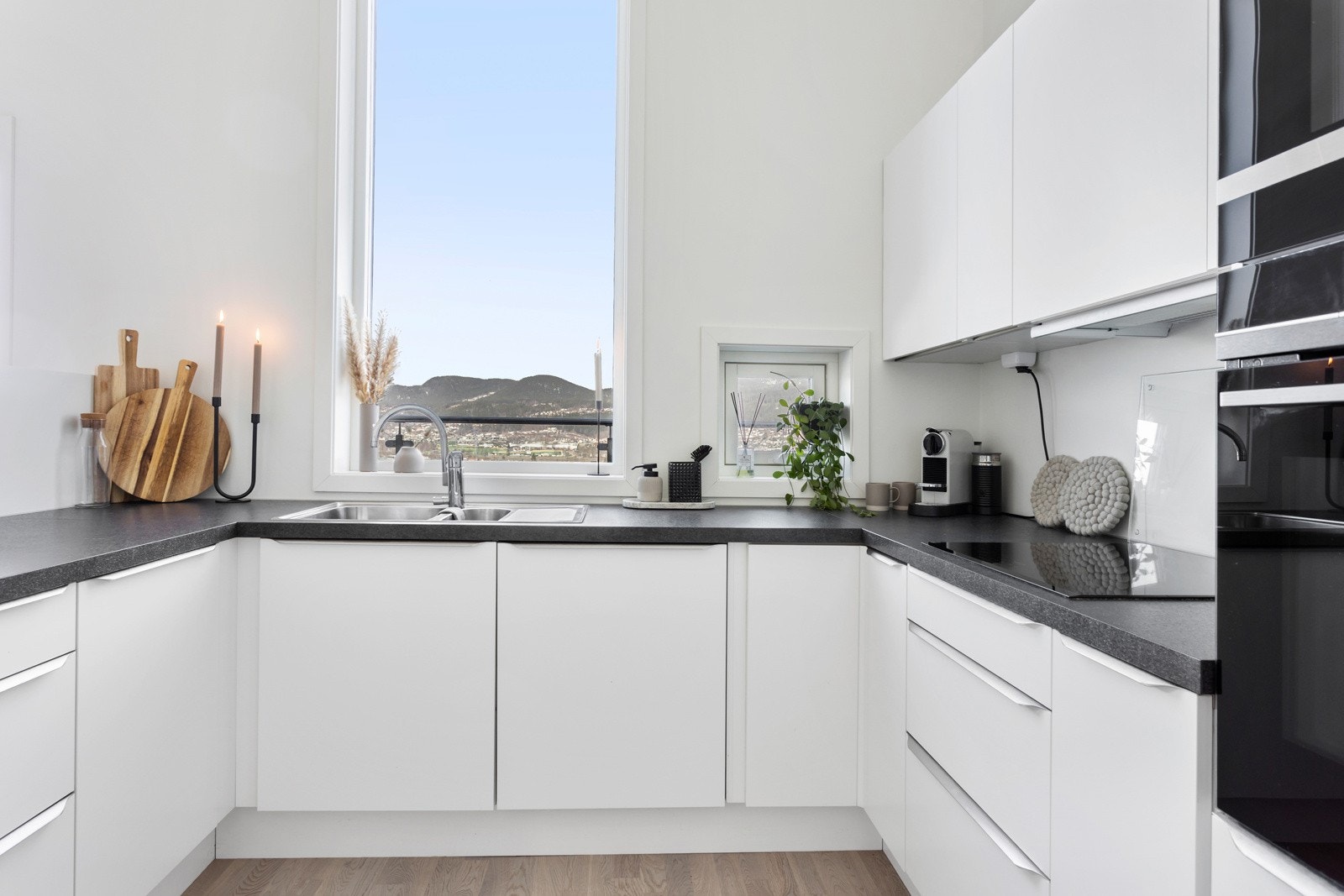 Kjøkkenet er innredet med slette fronter, laminert benkeplate og nedsenket oppvaskkum i metall med ett-greps blandebatteri Galleribilde