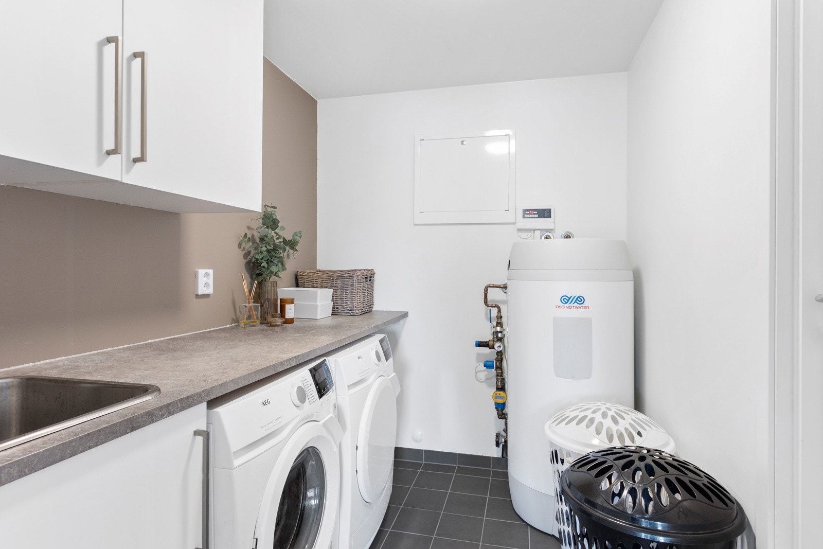 Vaskerom med flislagt gulv og varmekabler, laminert arbeidsbenk med nedsenket oppvaskkum. Opplegg for vaskemaskin og tørketrommel Galleribilde