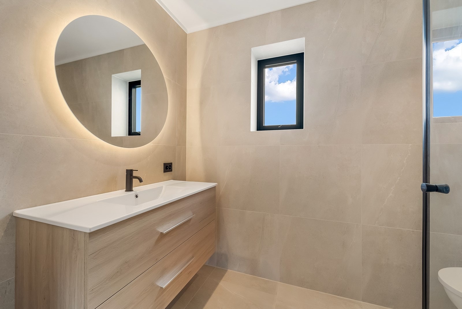 Moderne og stilrent utformet bad med baderominnredning, lyssatt speil, toalett og dusjløsning. Galleribilde