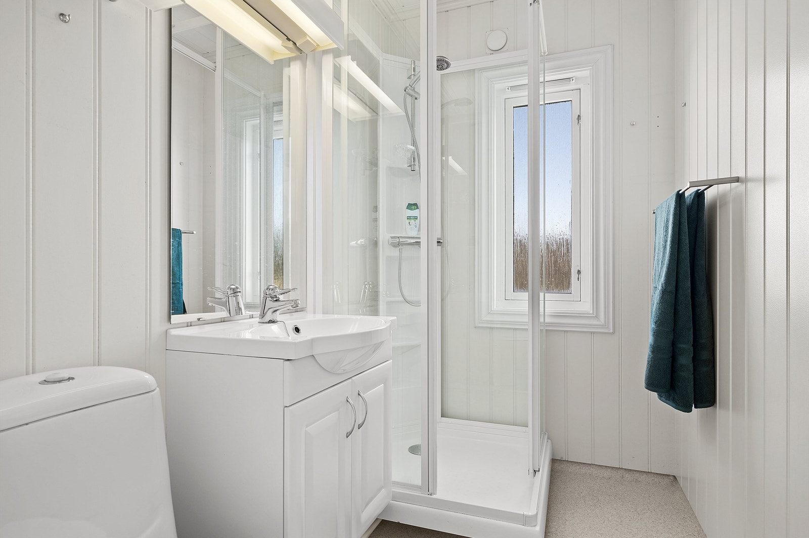 Badet er lyst og praktisk. Innredet med wc, enkel servant med underskap og dusjkabinett. Galleribilde