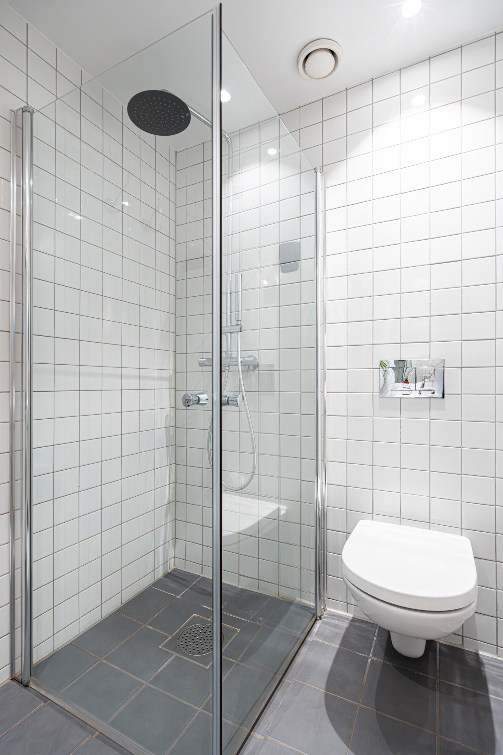 . Badet er utstyrt med dusjhjørne med dører i herdet glass, blandebatteri, vegghengt toalett med innebygd sisterne, servant med ett-greps blandebatteri, underskap og opplegg for vaskemaskin. Galleribilde