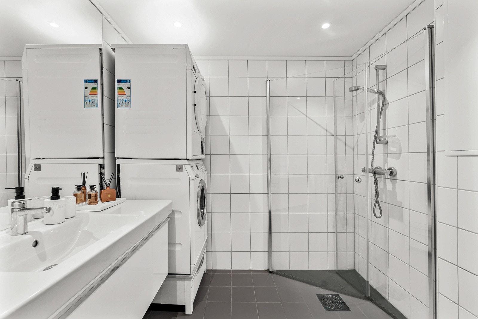 Baderommet er av god størrelse, flislagt fra topp til tå, og med behagelig gulvvarme. Innfellbare dusjdører i glass bidrar til et stilrent uttrykk og god romutnyttelse. Galleribilde