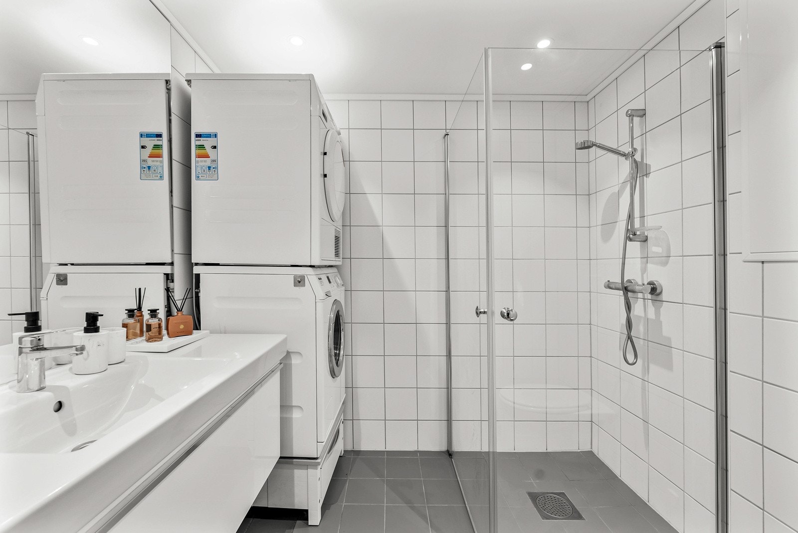 Baderommet er av god størrelse, flislagt fra topp til tå, og med behagelig gulvvarme. Innfellbare dusjdører i glass bidrar til et stilrent uttrykk og god romutnyttelse. Galleribilde