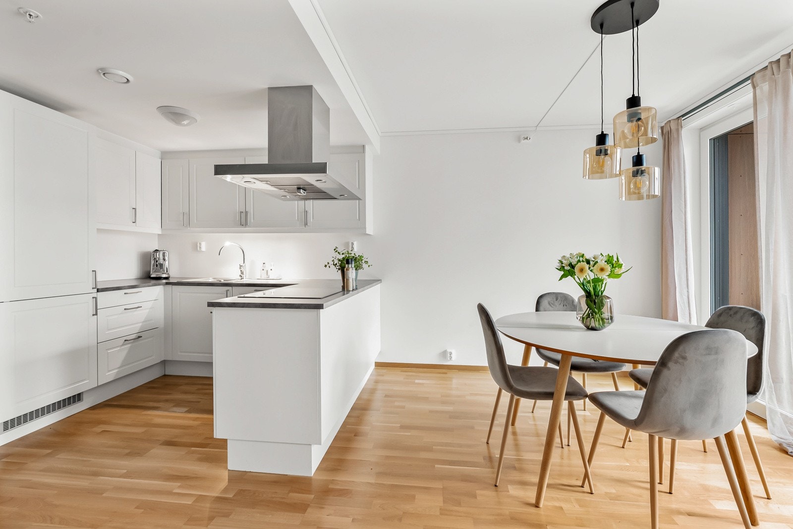 Innredningen har hvite, takhøye skap og benkeplate av laminat. Hesteskoutformingen bidrar til en effektiv og optimal arbeidsflyt. Galleribilde