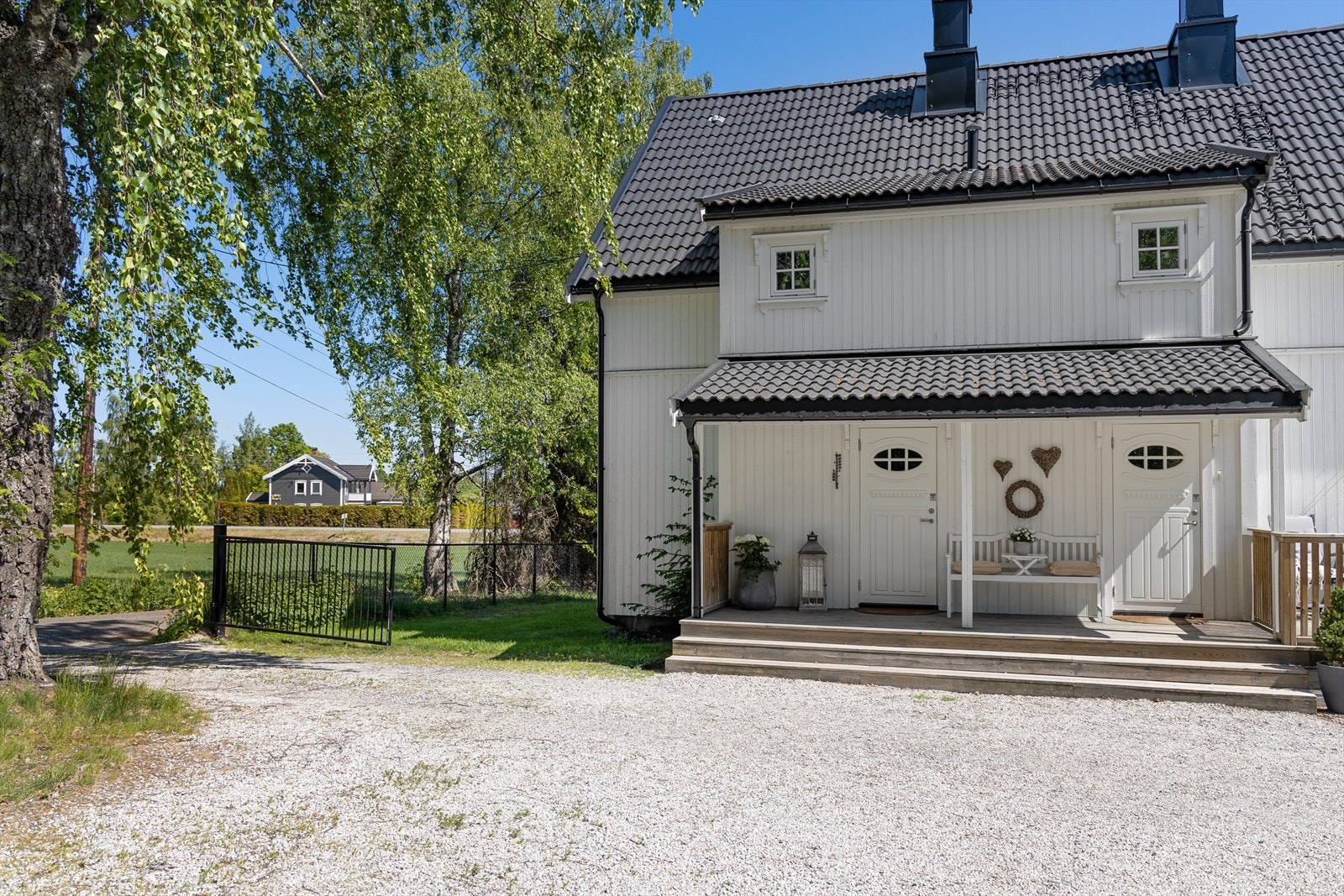 Eneboligen har et flott inngangsparti med adkomstterrasse, overbygg, samt hvite inngangsdører til både entré og bod. Galleribilde