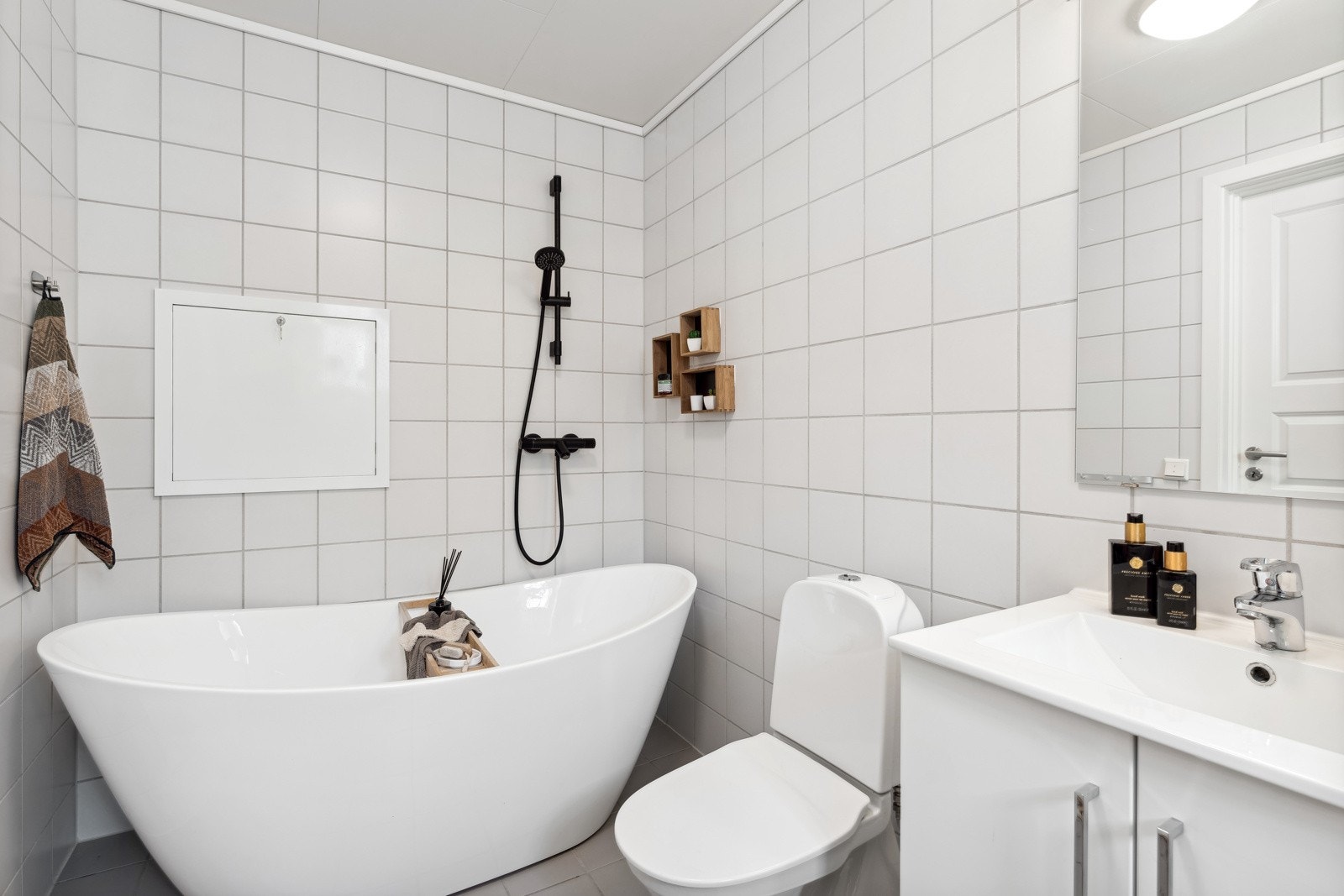 Innredningen består videre av flere skap, speil, opplegg for vaskemaskin, toalett og badekar med et stilig sort dusjarmatur. Galleribilde