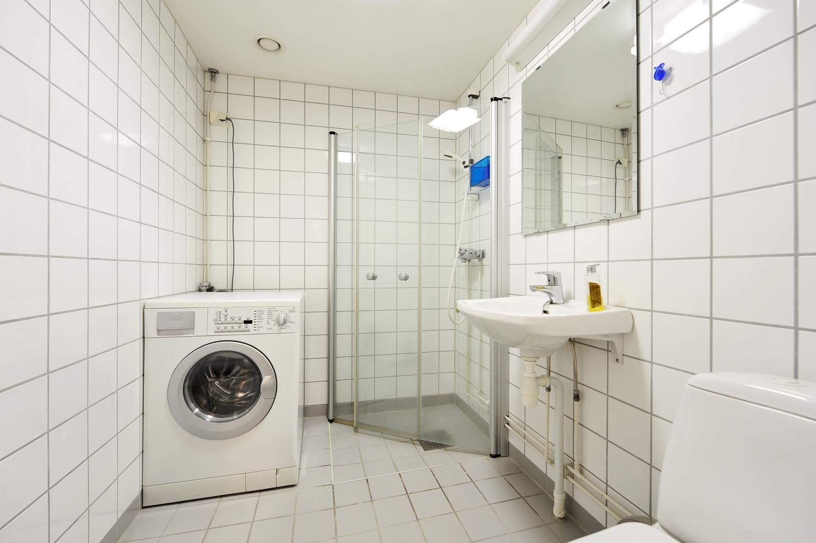Flislagt bad med, dusjdører, varmekabler og vaskemaskin. Galleribilde