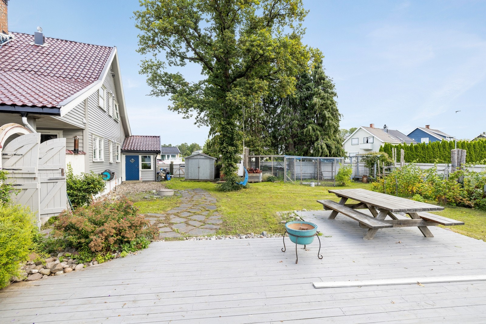 Hagen er opparbeidet med blomsterbed, busker, trær og en terrasse Galleribilde