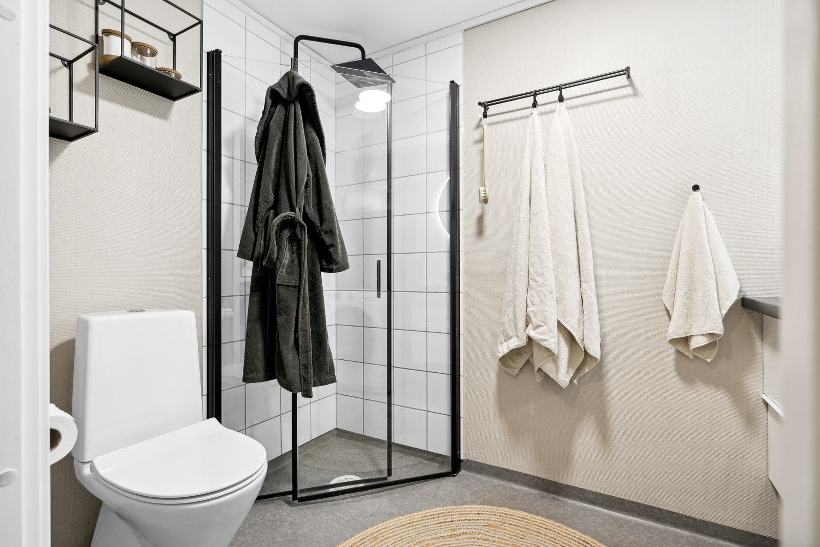 Pent baderom utstyrt med toalett, dusj med innfellbare vegger, servant med underskap, lysbesatt speil og opplegg for vaskemaskin. Galleribilde
