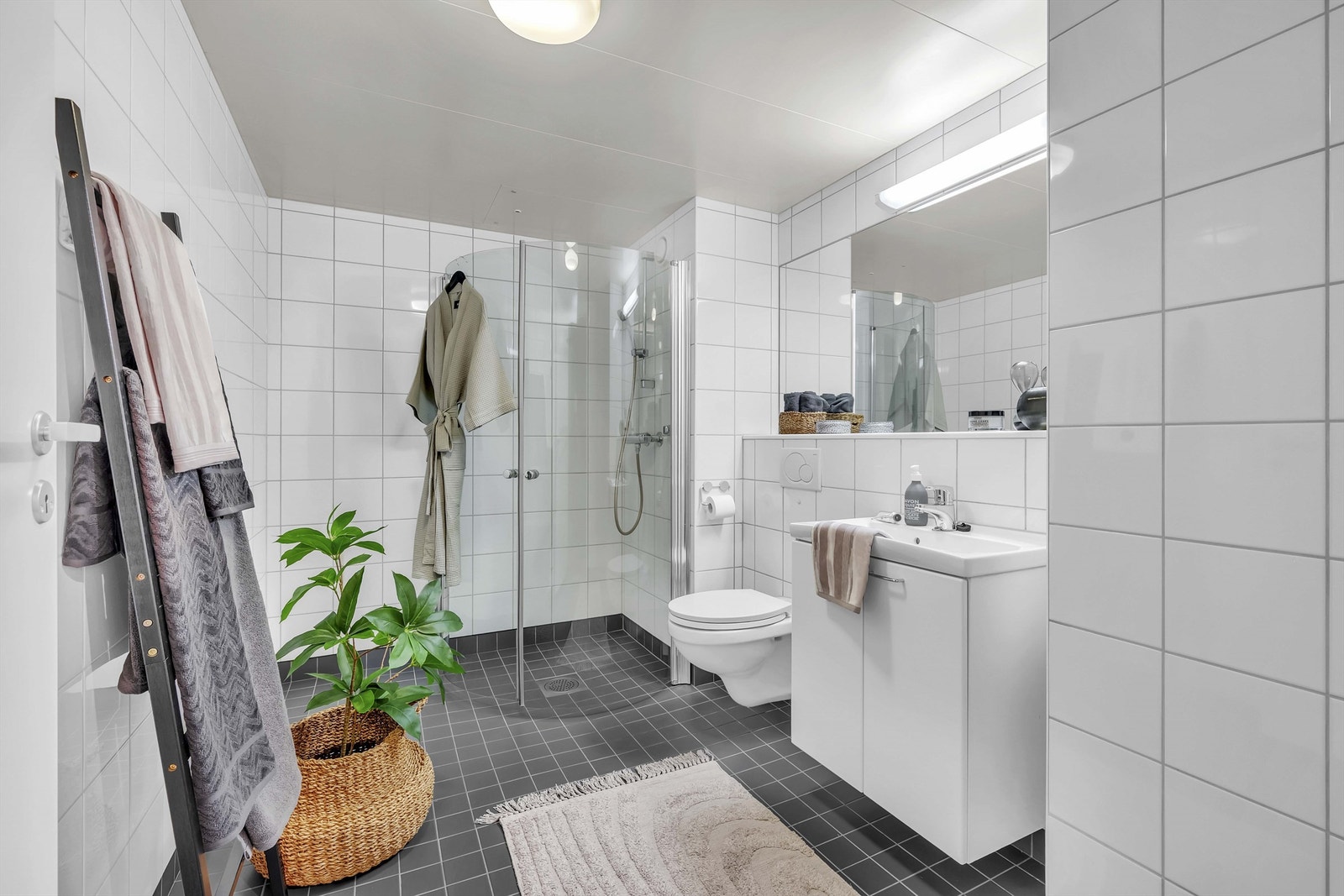 Servantskap med slette fronter og 1-greps blandebatteri. Speil med belysning montert på vegg. Galleribilde