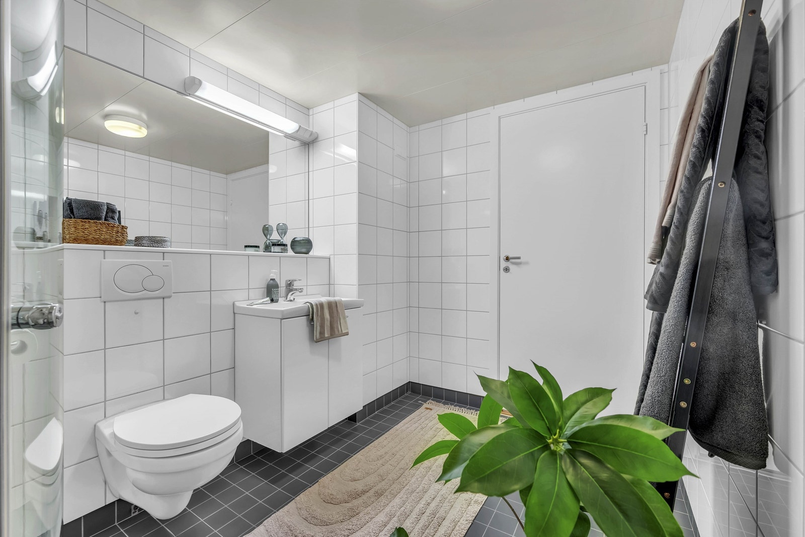 Dusj med avrundede dusjdører og hånddusj. Vegghengt toalett med innebygget sisterne. Opplegg for vaskemaskin. Galleribilde