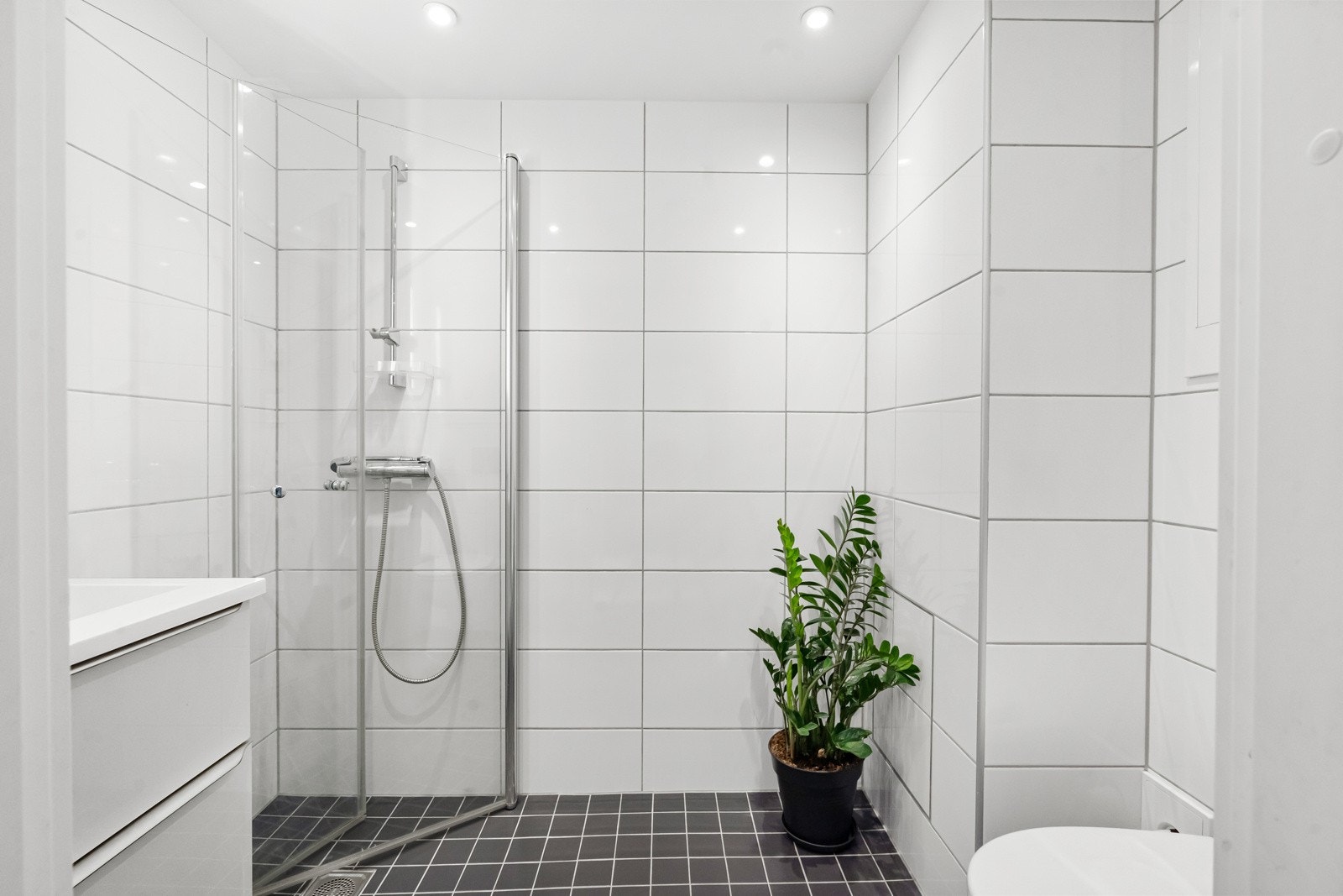 Pent og moderne baderom fra 2018 i boligens 1. etasje. Innredning utført med flislagte vegger, flislagt gulv med varme, samt nedsenket himling med downlights. Galleribilde