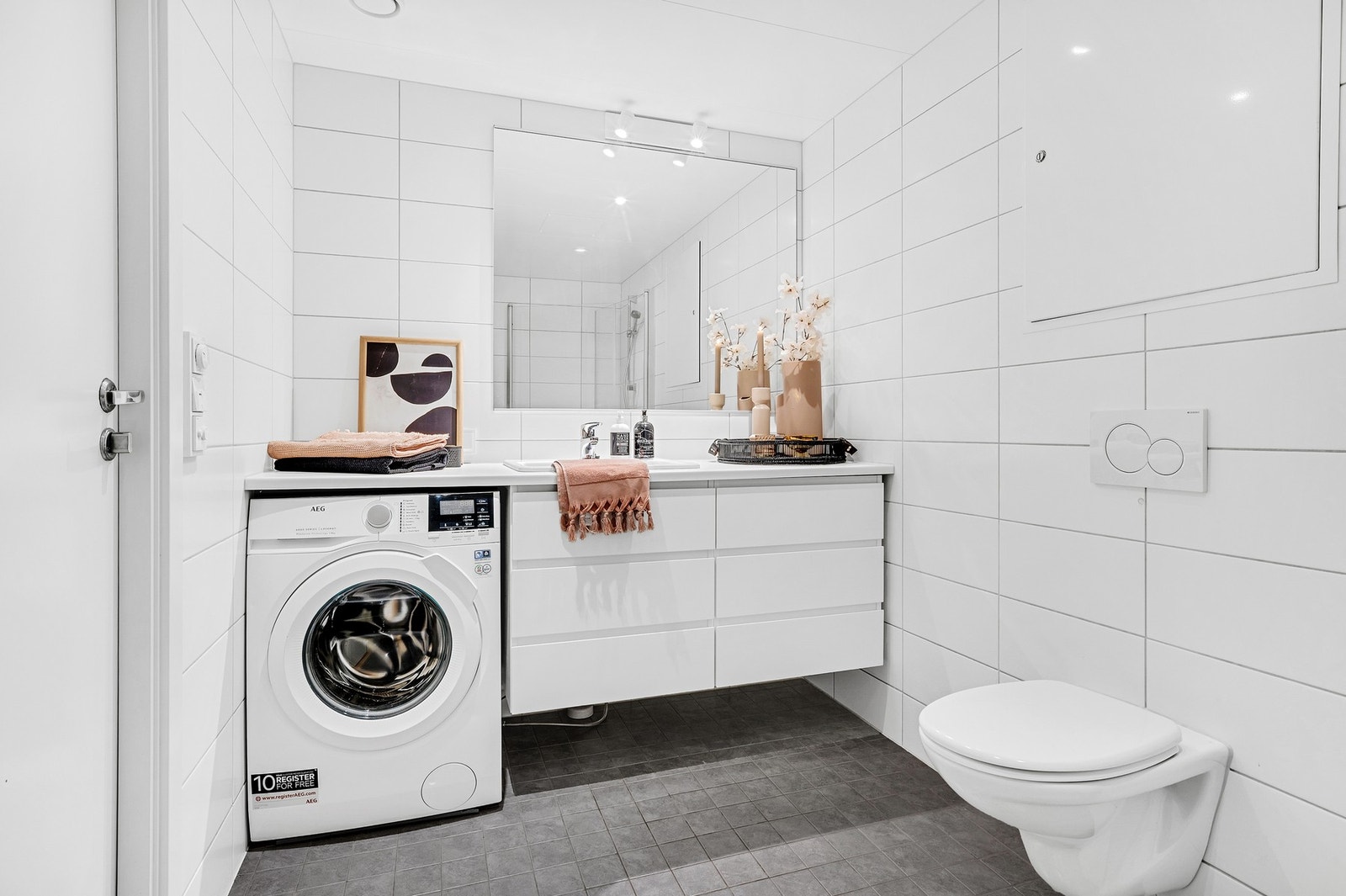 Bad med dusjhjørne, klosett, servant og opplegg for vaskemaskin. Galleribilde