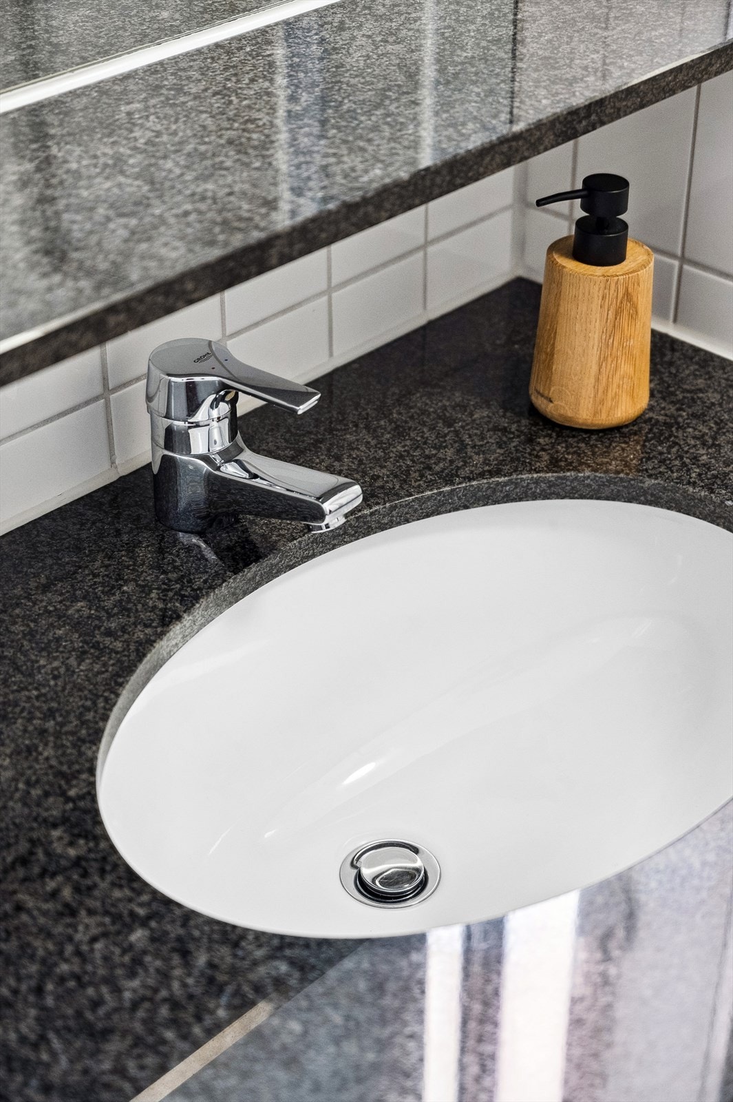 Innredning med steinplate og underlimt servant, veggmontert toalett, dusjnisje med skyvedører og opplegg for vaskemaskin. Galleribilde