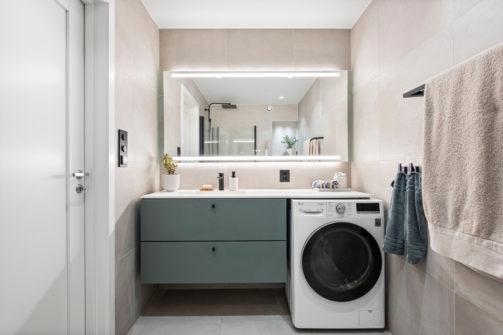 Badet er utstyrt med servantinnredning med skuffer, samt Corian benkeplate fra Kuma. Under benkeplaten er det også opplegg og plass til vaskemaskin (kombi vask/tørk medfølger salget). Det er også speil med belysning over servanten Galleribilde