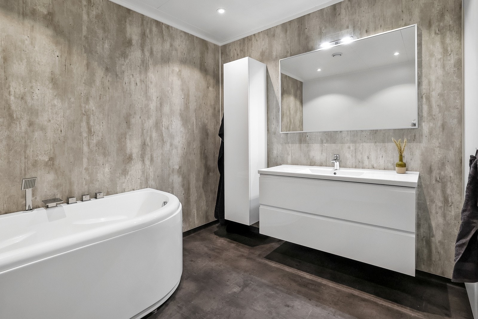 Badet i 1. etasje har en hvit vegghengt baderomsinnredning med speil og sideskap Galleribilde
