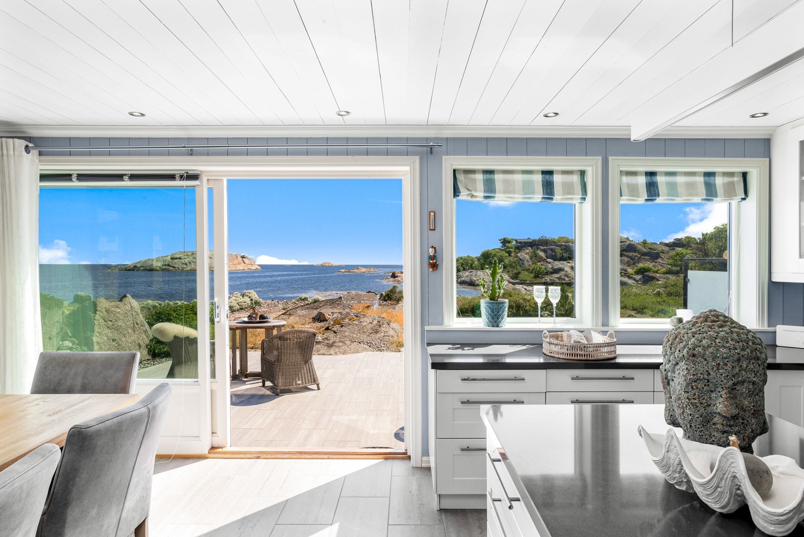 Stue-/spisestuen med åpen kjøkkenløsning og utgang til terrasse mot sjøen. Galleribilde