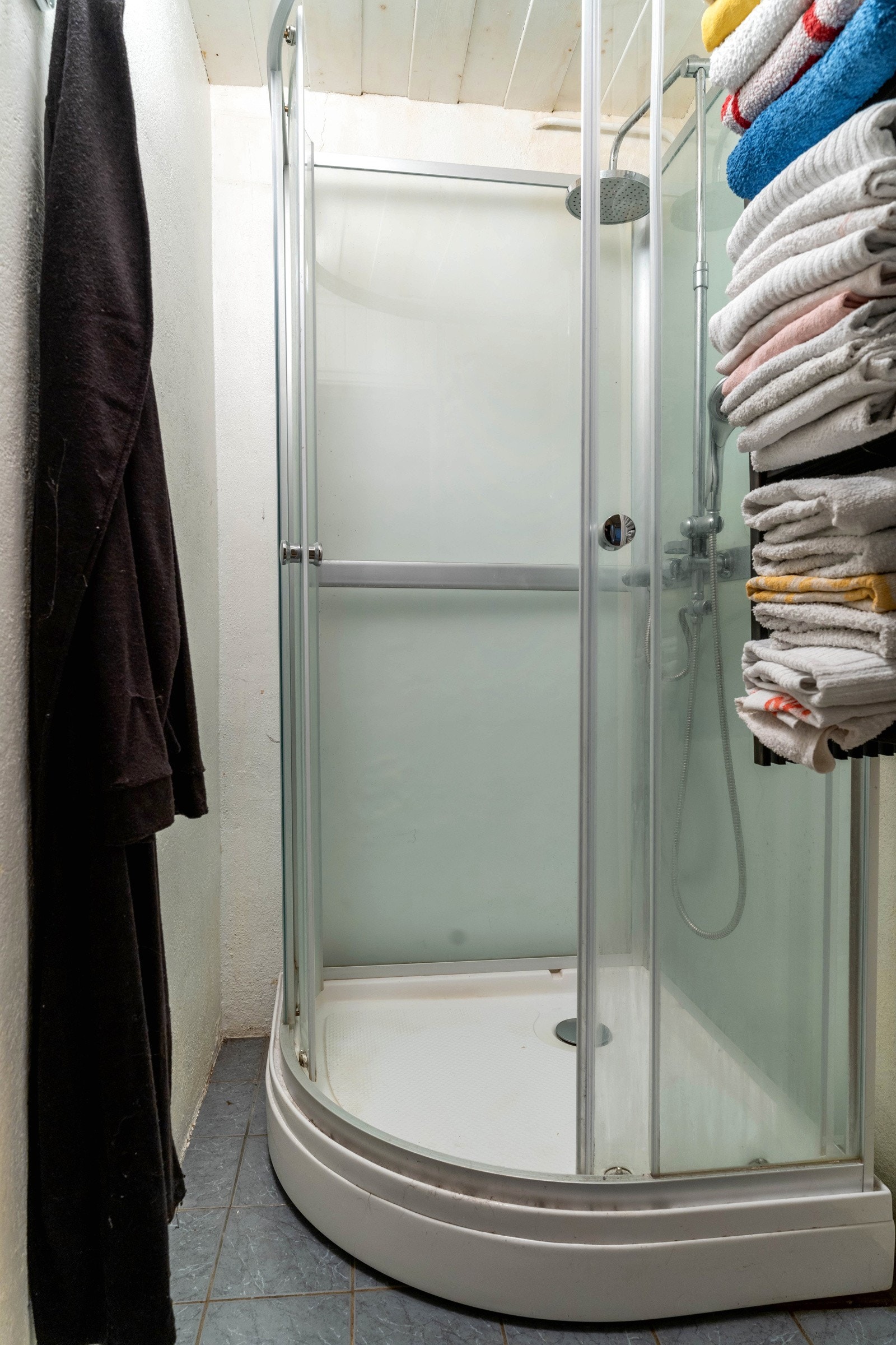 Lite dusjrom med dusjkabinett. Flis på gulvet med varmekabel. malt puss på vegger, panel i himling. Galleribilde