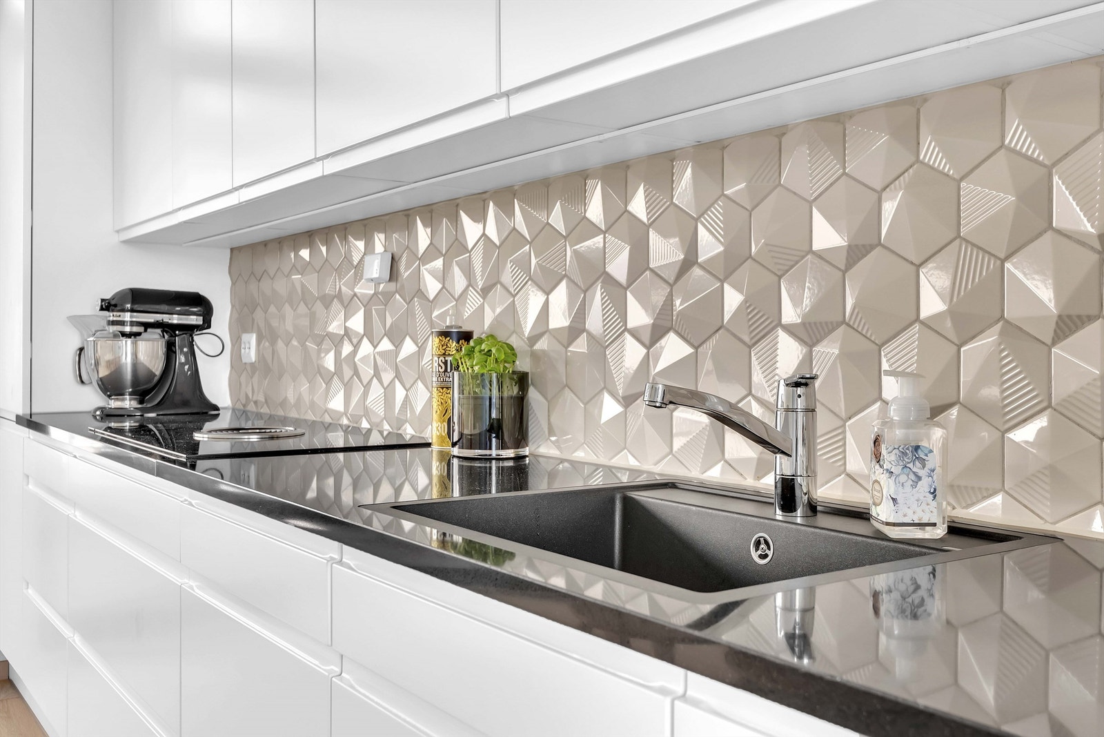 Kjøkkeninnredning med hvite glatte fronter. Benkeplater av laminat. Nedfelt oppvaskkum med ett-greps armatur. Flislagt mellom kjøkkenbenk og overskap. Galleribilde