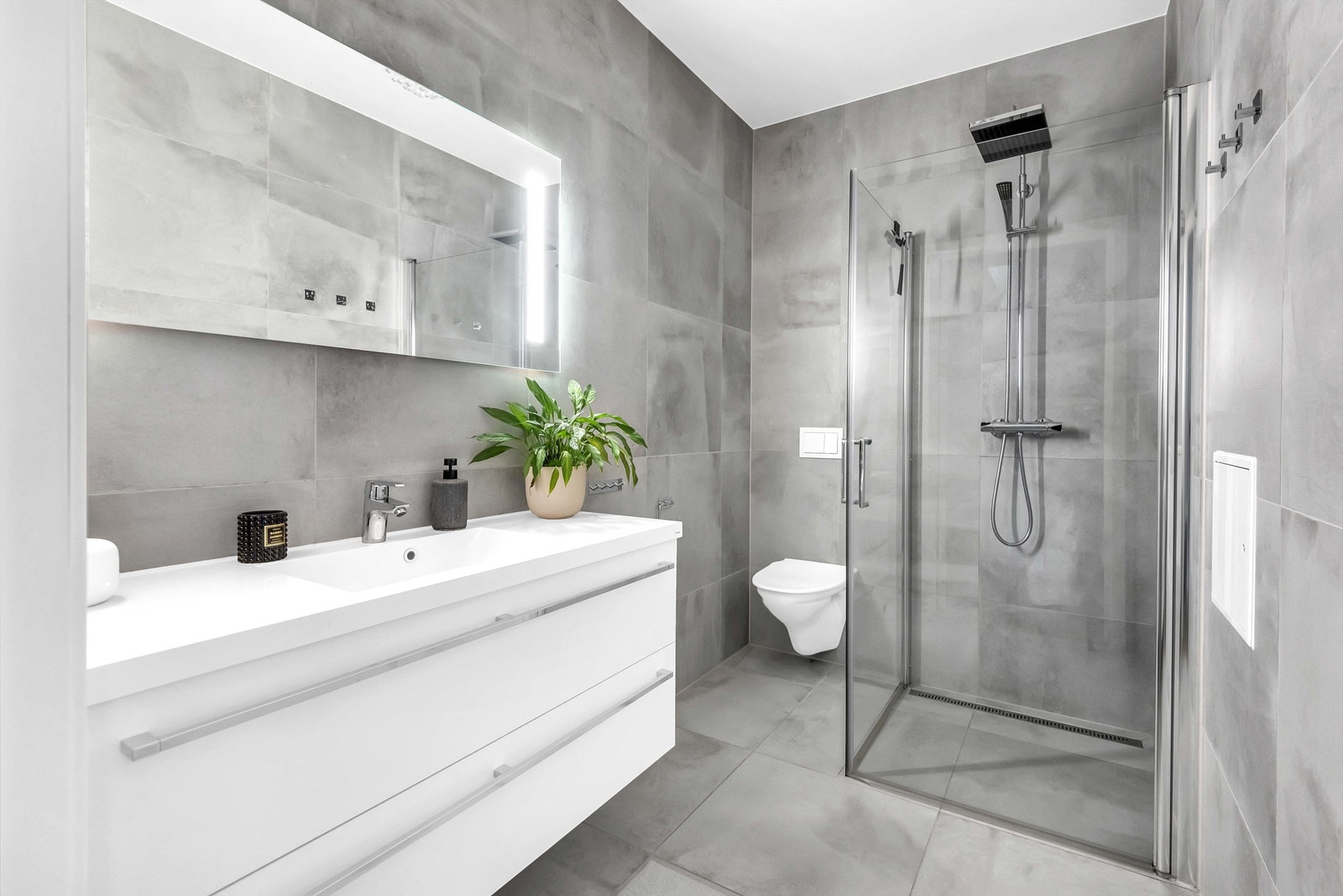 Pent bad fra byggeår. Flislagt gulv med elektrisk gulvvarme. Flislagte vegger. Malt himlingflate. Vegghengt servantskap med heldekkende servant og ettgreps armatur. Speil over servant med overlys. Galleribilde