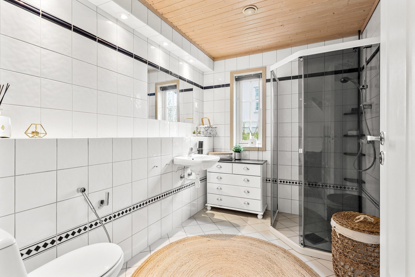 Fra hallen er det adkomst til et flislagt bad av god størrelse. Badet er utstyrt med servant, speil, stikk og en dusjsone med dusjing direkte på gulv og vegg. Galleribilde