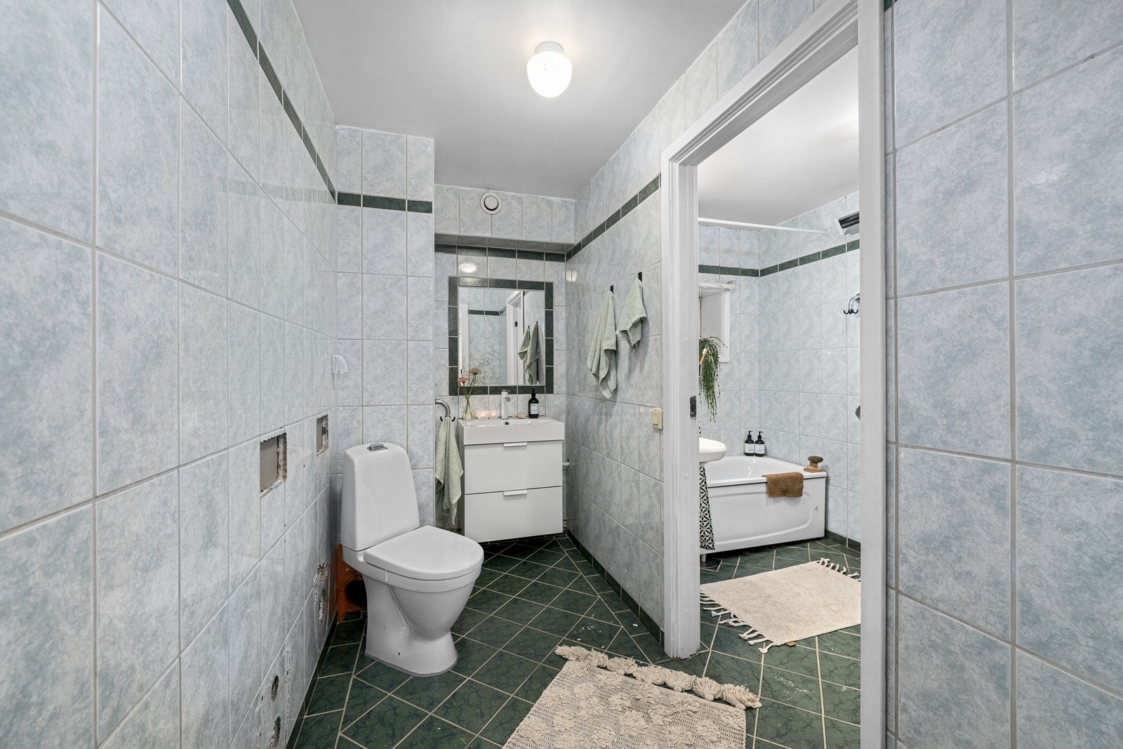Fra gangen er det inngang til et toalettrom, med videre åpning inn mot badet. Rommene er av eldre dato, og modernisering/renovering må påregnes. Galleribilde