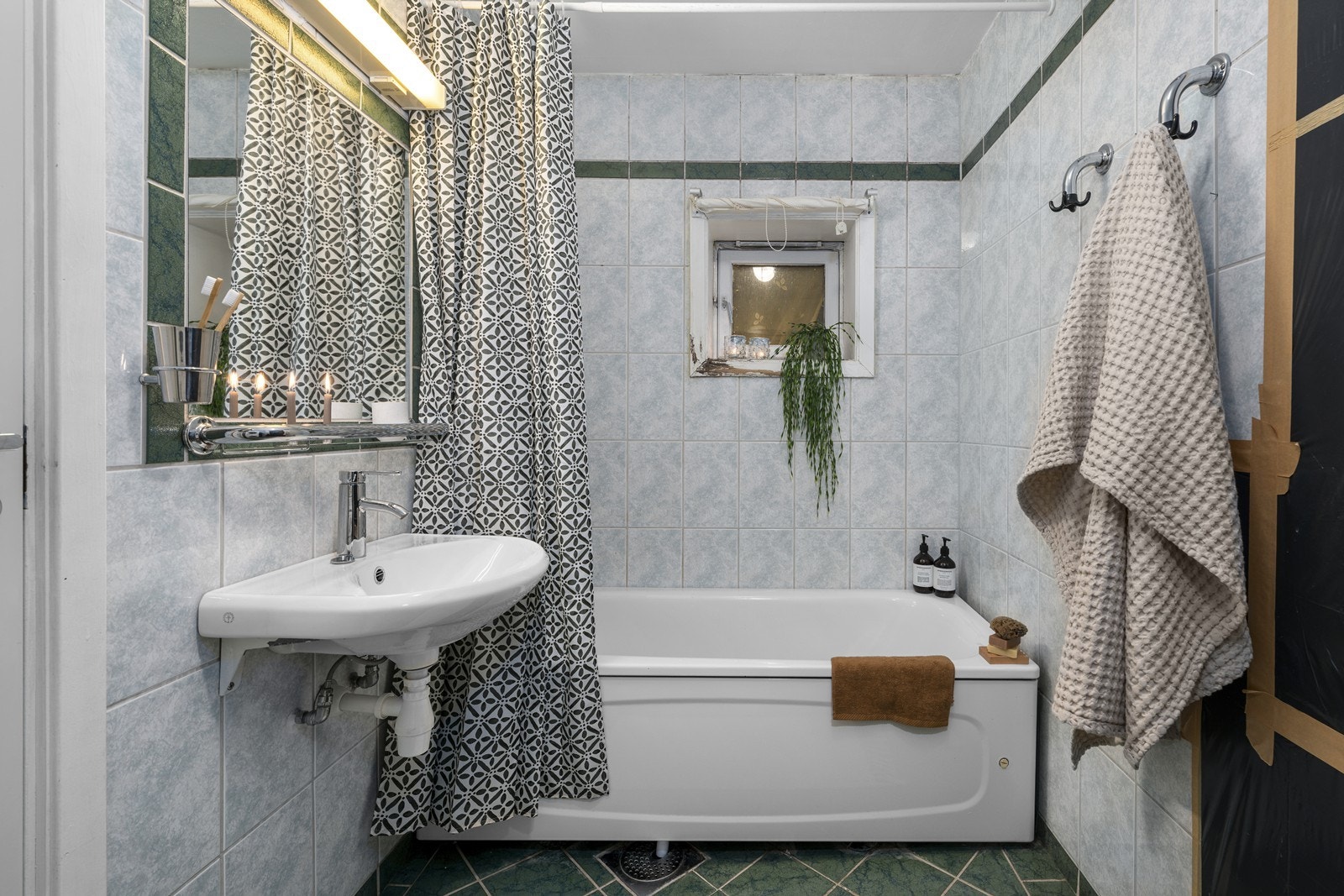Bad og toalettrom har flislagt gulv, flislagte vegger og malt slett himling. Badet er utstyrt med innredning bestående av nedfelt servant med underskuffer og 1-greps blandebatteri, gulvstående toalett, badekar og opplegg for vaskemaskin. Galleribilde