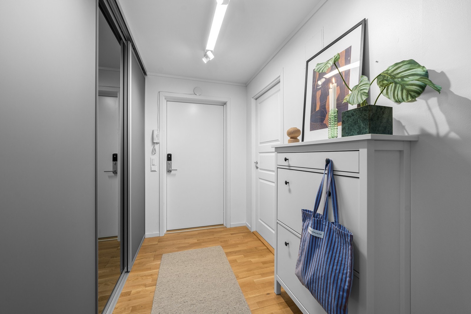 Boligen har en lys entré med god plass til yttertøy i smart skyvedørsgarderobe. Dørcalling med åpner gjør det enkelt å slippe inn gjester fra bakkeplan. Galleribilde