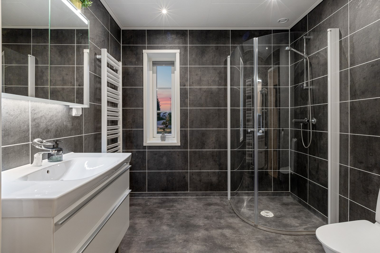 Boligen har et delikat bad med belegg på gulv og våtromsplater på vegger. Badet har mekanisk balansert ventilasjon, gulvvarme og det er montert downlights i himling. Galleribilde