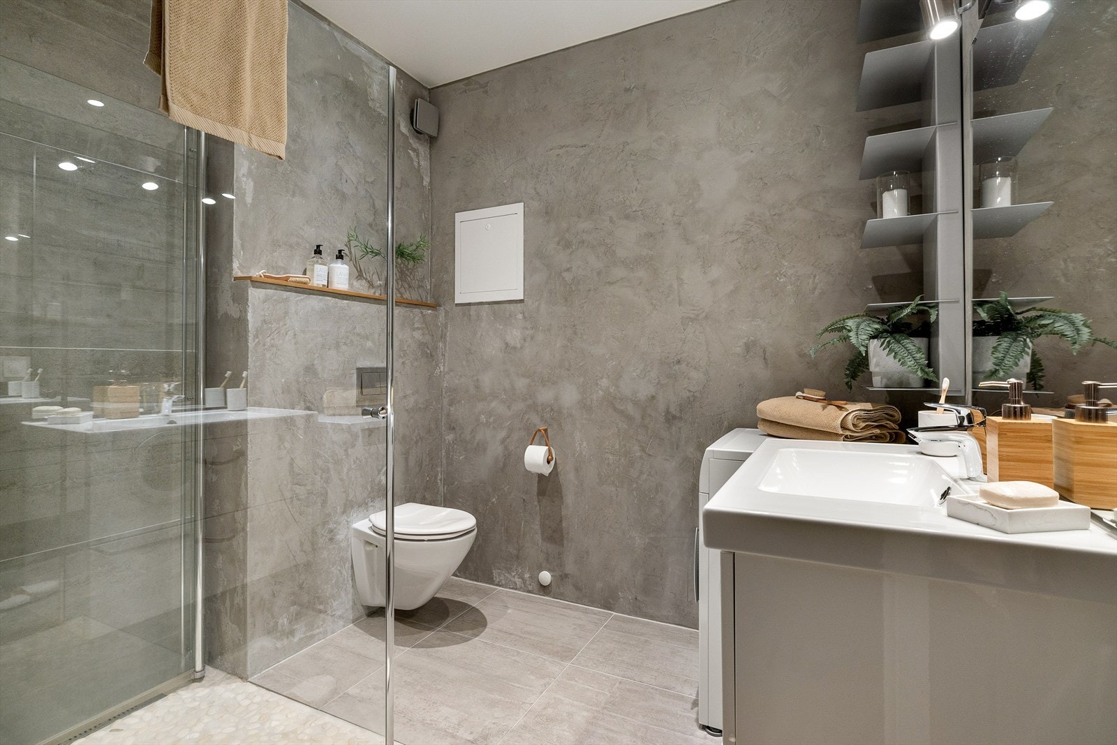 Bad med fliser og microsement på vegger og fliser på gulv. Badet har downlights i himling og varmekabler i gulv. Galleribilde