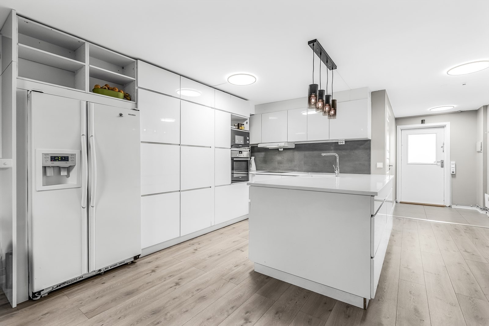 Lekkert kjøkken med hvite høyglans fornter og benkeplate. Galleribilde