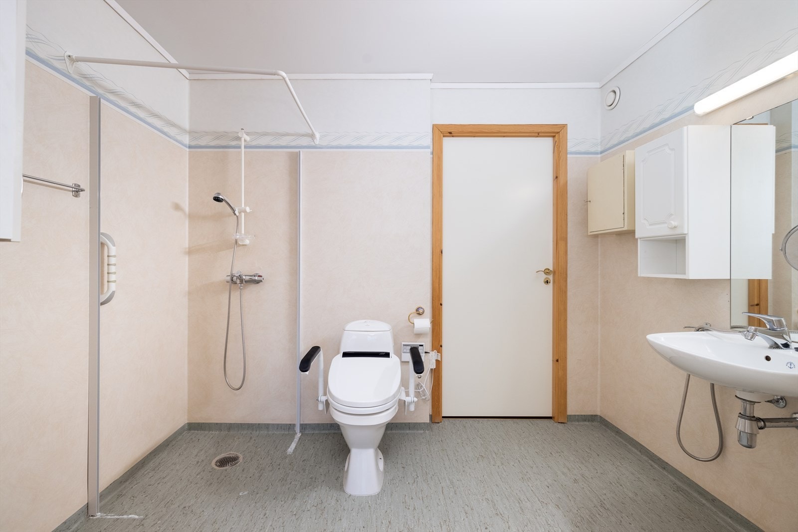 Leiligheten har et romslig bad med varmekabler, hvor det er adkomst både fra entrèen og fra soverommet. Badet er innredet med servant, overskap og speil med overlys og el-stikk. Det er etablert dusjhjørne hvor det er opplegg til forheng. Galleribilde