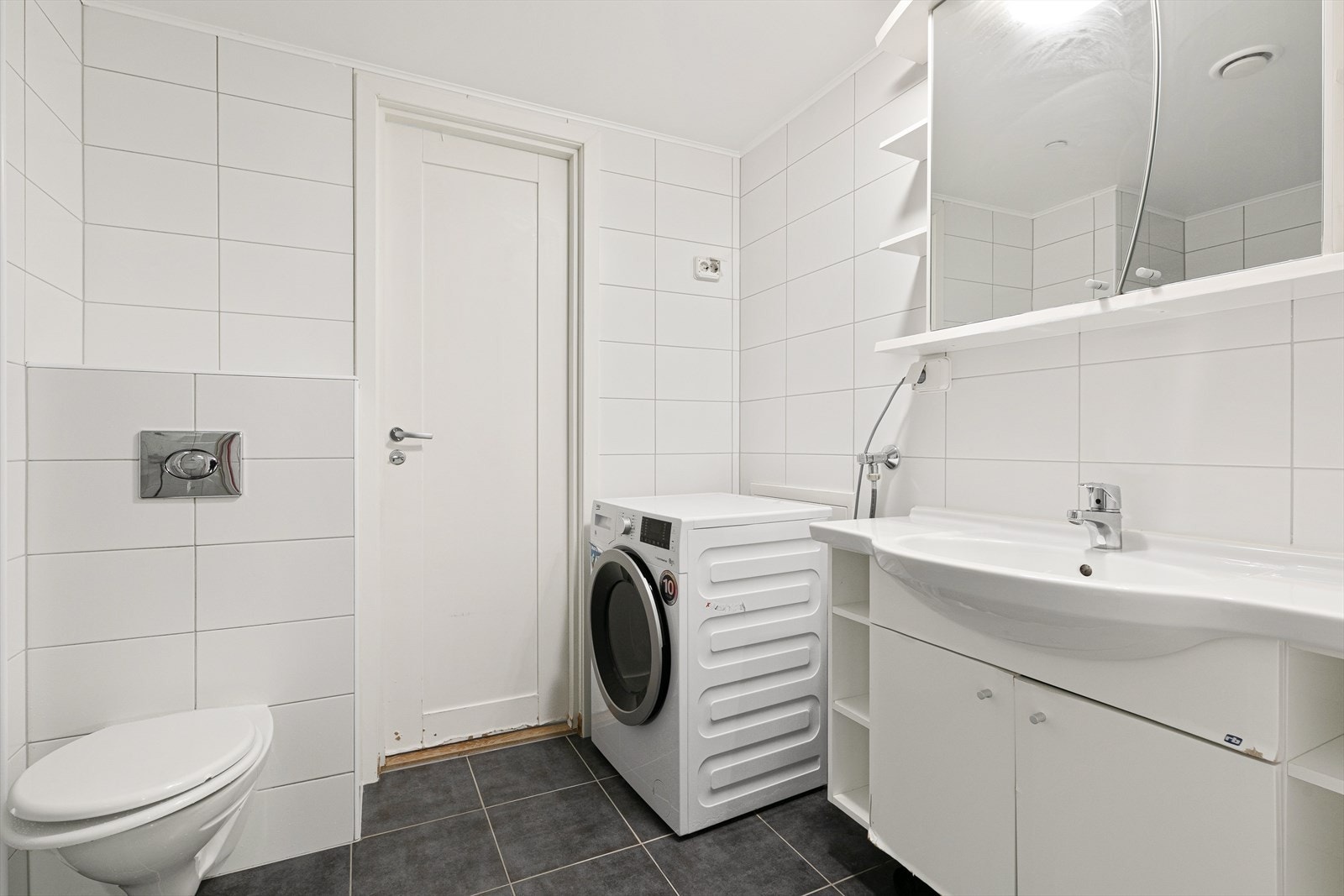 Badet består av vegghengt klosett, dusjhjørne og servant med over- og underskap. Her er det også opplegg for vaskemaskin og/eller tørketrommel. Galleribilde