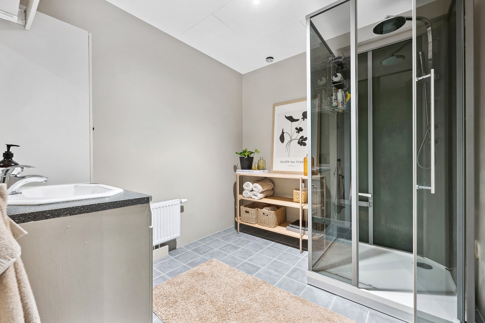 Tidløst og romslig baderom med flislagt gulv, speil med lysarmatur, høyskap og dusjkabinett Galleribilde