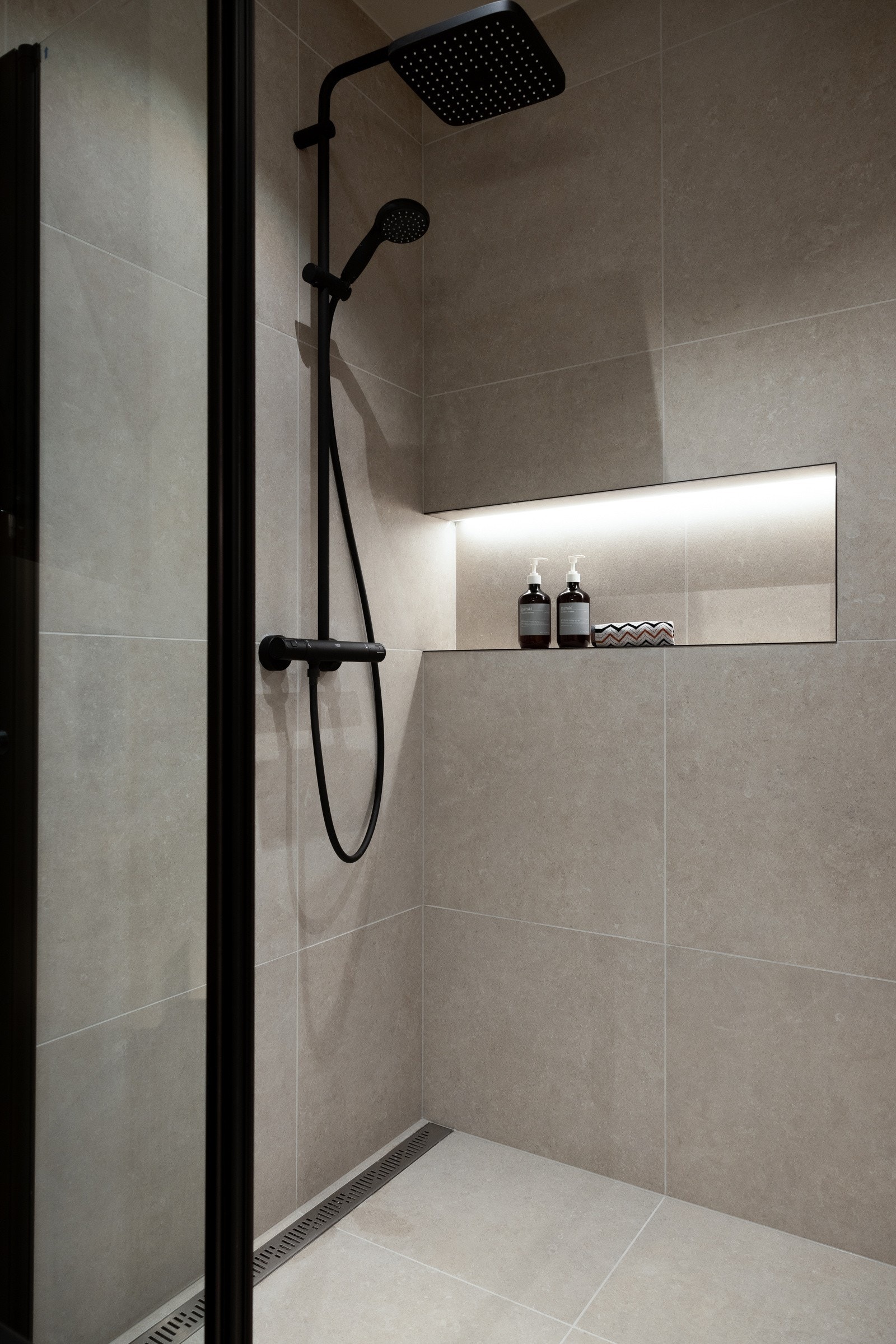 Stor dusjsone med både hånddusj og regnfallsdusj fra Grohe. Designsluk langs veggen. Galleribilde