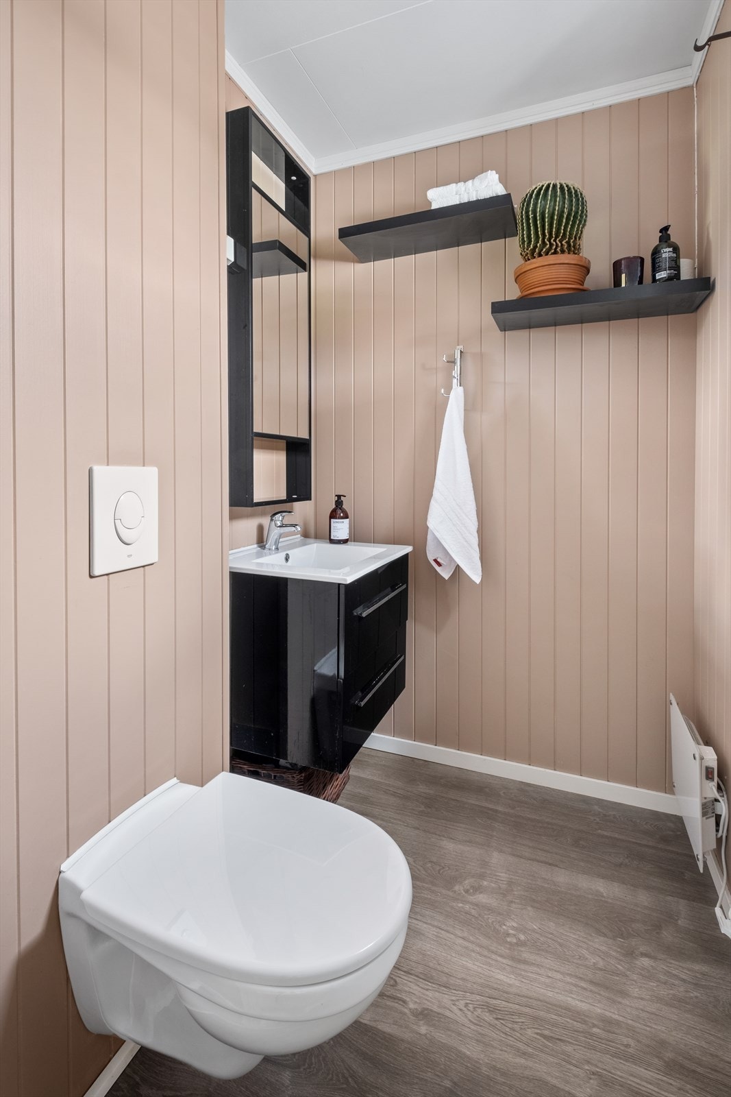 Vegghengt toalett med laminat på gulv og servant Galleribilde