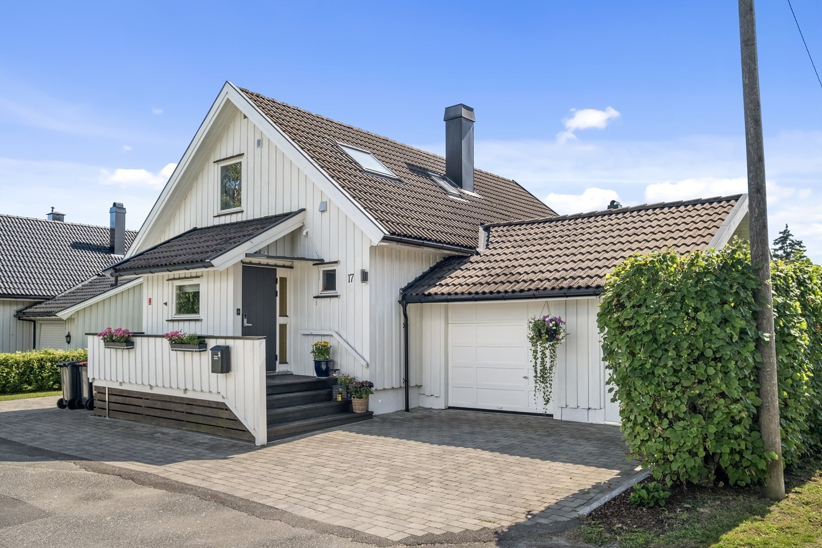 Belegningsstein i gårdsplass som er lagt i senere tid og garasje med elbillader og tilhørende bod Galleribilde