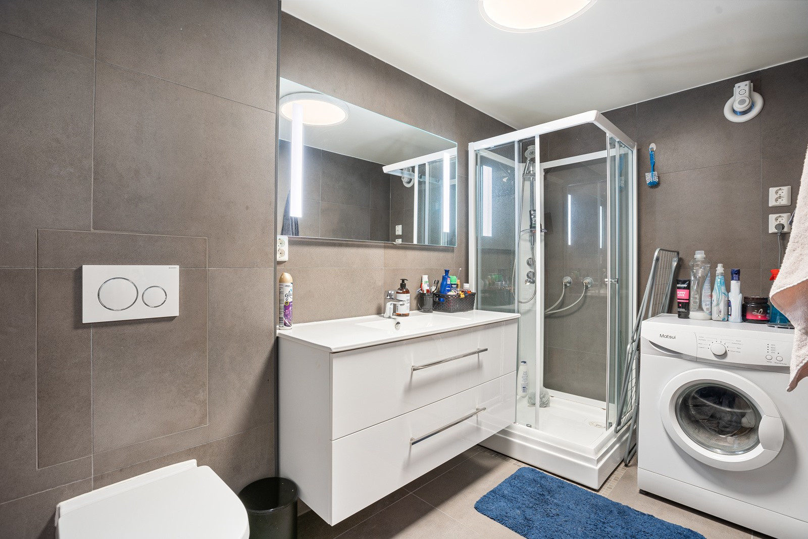 Moderne bad i underetasje med vegghengt toalett, dusj og opplegg til vaskemaskin