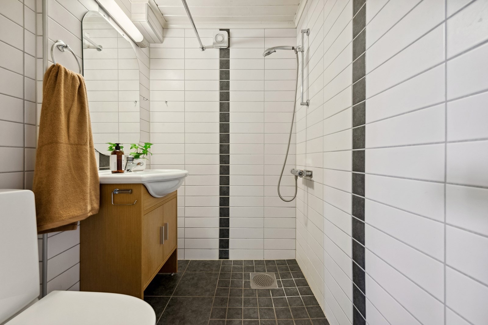 Badet i sokkeletasjen er fra 1997/98 hvor det er lagt nye fliser over opprinnelige fliser i 2012. Badet er utstyrt med dusjsone med forheng, WC og servant med skap i rommet. Galleribilde
