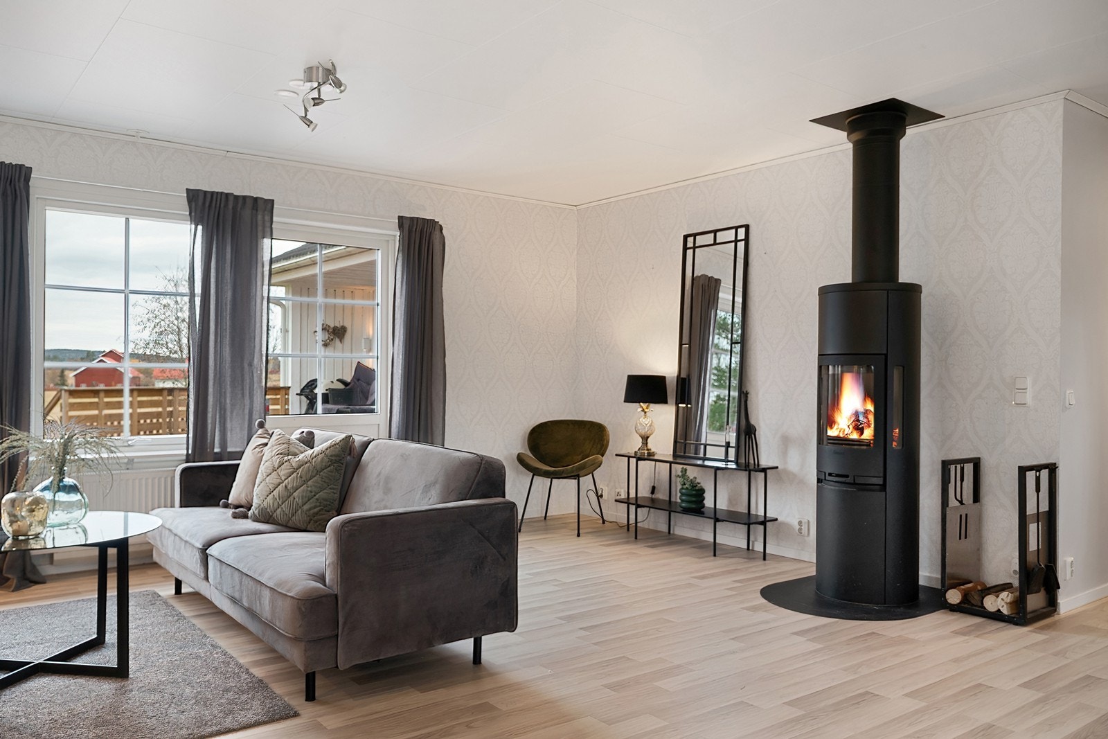 Sentralt i rommet er en moderne, høyreist peisovn som sørger for ekstra hygge og varme. Galleribilde