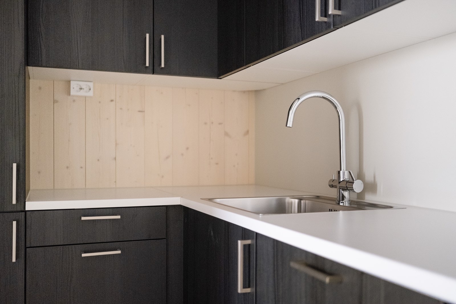 Sort kjøkken med hvit benkeplate sørger for et moderne preg i leiligheten. Galleribilde