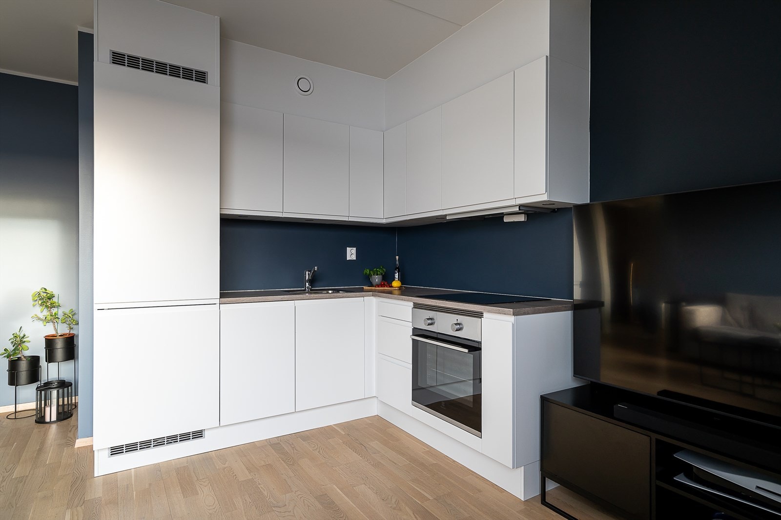 Kjøkkeninnredning med hvite slette fronter, laminert benkeplate og integrerte hvitevarer. Galleribilde