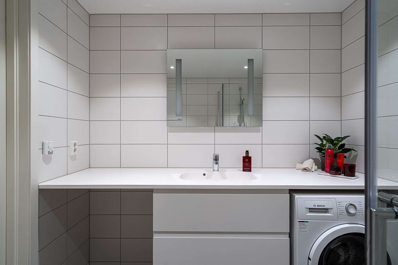 Innredningen består av et servant med underskap for oppbevaring, speil, dusjhjørne med innfellbare glassdører og vegghengt toalett. Galleribilde