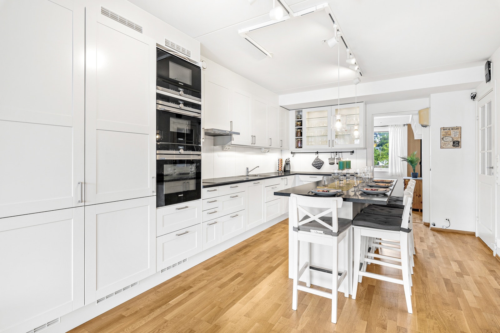 Godt belyst kjøkken med kjøkkenskap, øy og integrerte hvitevarer Galleribilde