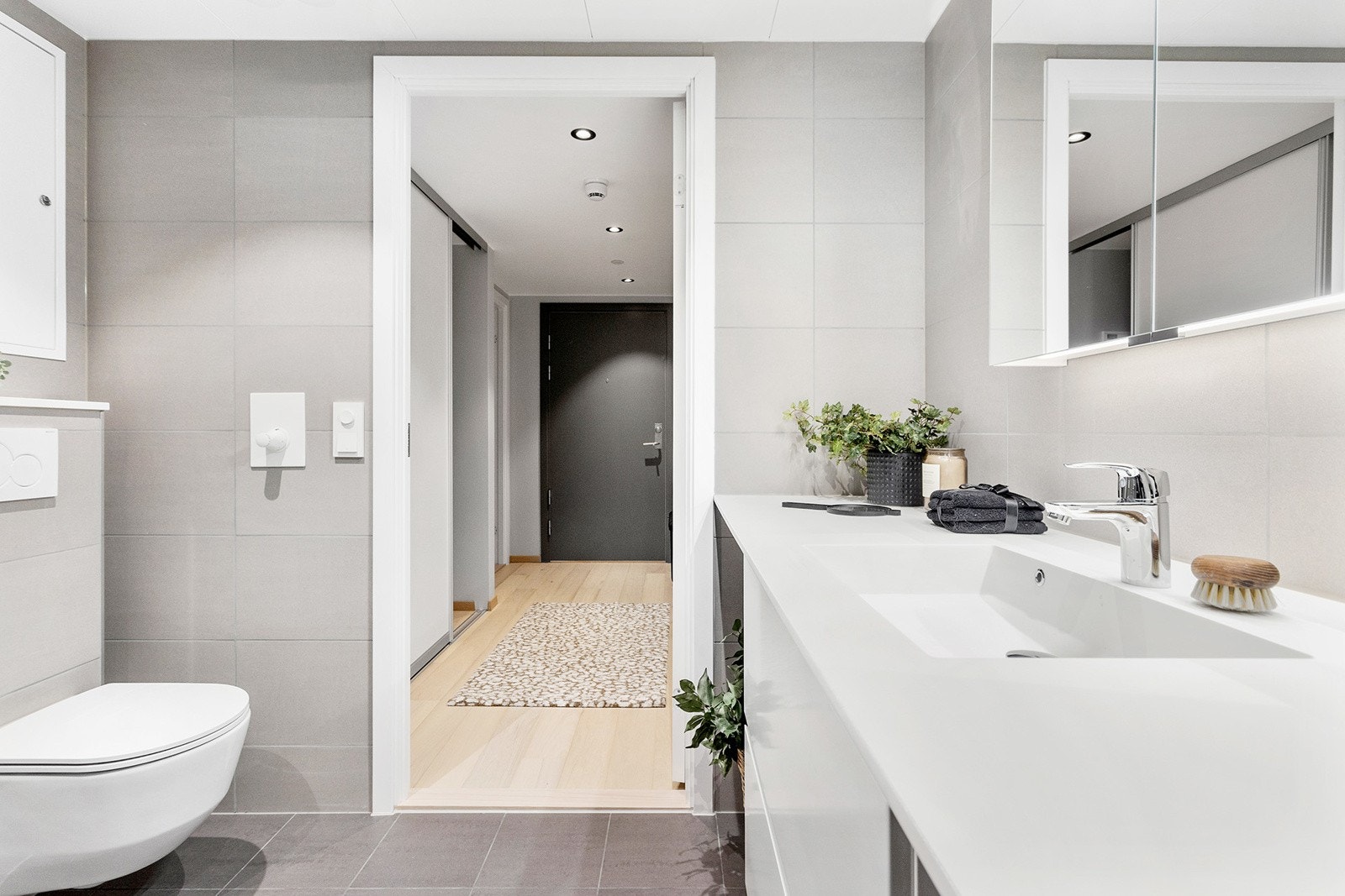 Bad har dusjhjørne med innfellbare glassdører, flott baderomsinnredning og vegghengt toalett. Galleribilde