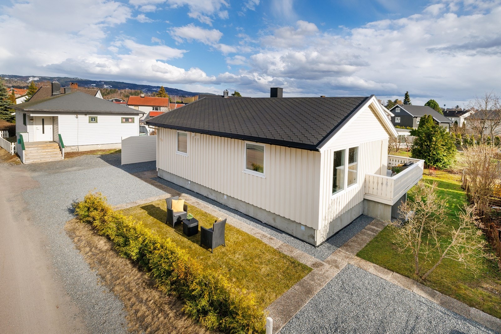 Eiendommen er pent opparbeidet med hekk, plen og steinheller. Gruset gårdsplass hvor det også er parkeringsmulighet for utleiedelen på høyre hånd. Galleribilde