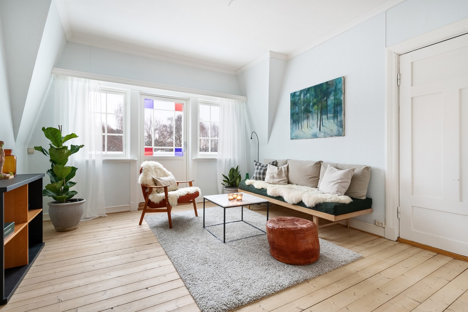Loftstue med lysmalt strie på veggene med blåskjær i, og heltregulv. Stuen er lys, og får godt med dagslys inn fra vinduene og balkongdøren. Galleribilde