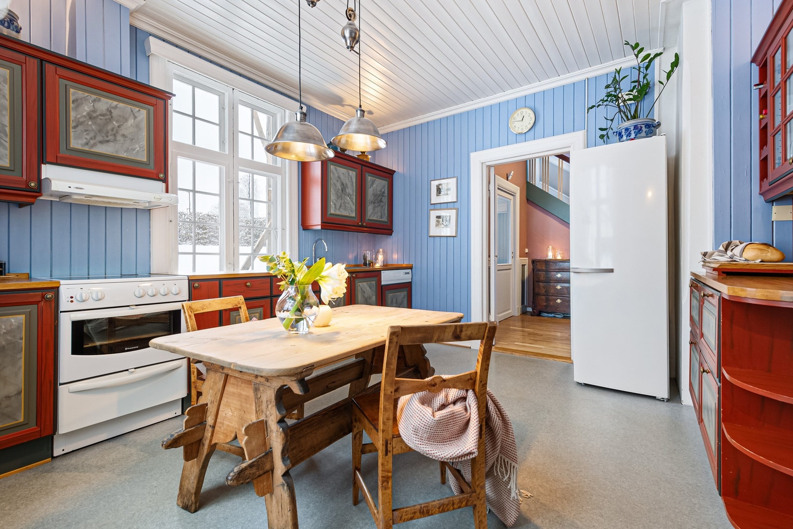 Kjøkkenet har blåmalt panel på veggene og grått spraglete belegg på gulvet. Heltre, malt kjøkkeninnredning med heltre benkeplater. Galleribilde