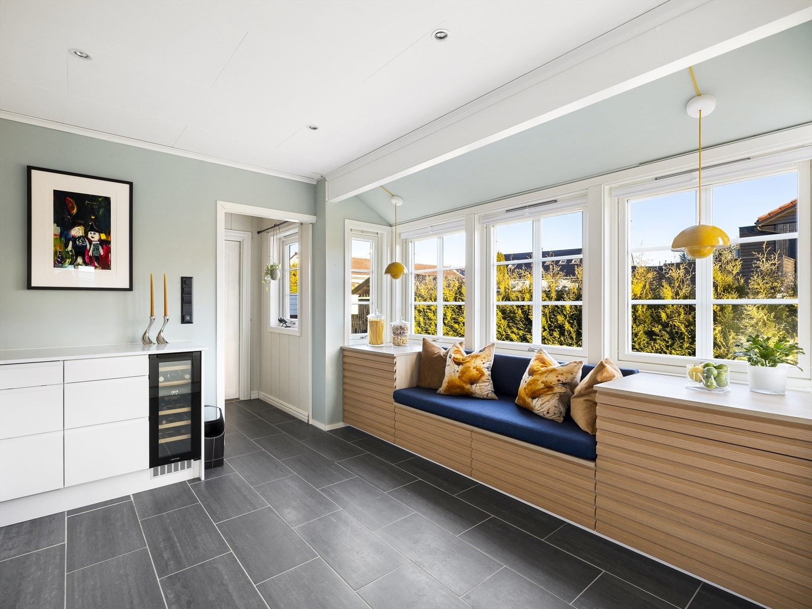 Fliser i gulv, samt varmekabler i gulv, helt bort til bi-inngang og spotter i tak. Fronter i eik som bryter opp utrykket og står pent i stil til kjøkkenet. Praktisk nedfelt sitteplass i kjøkken innredning. Galleribilde