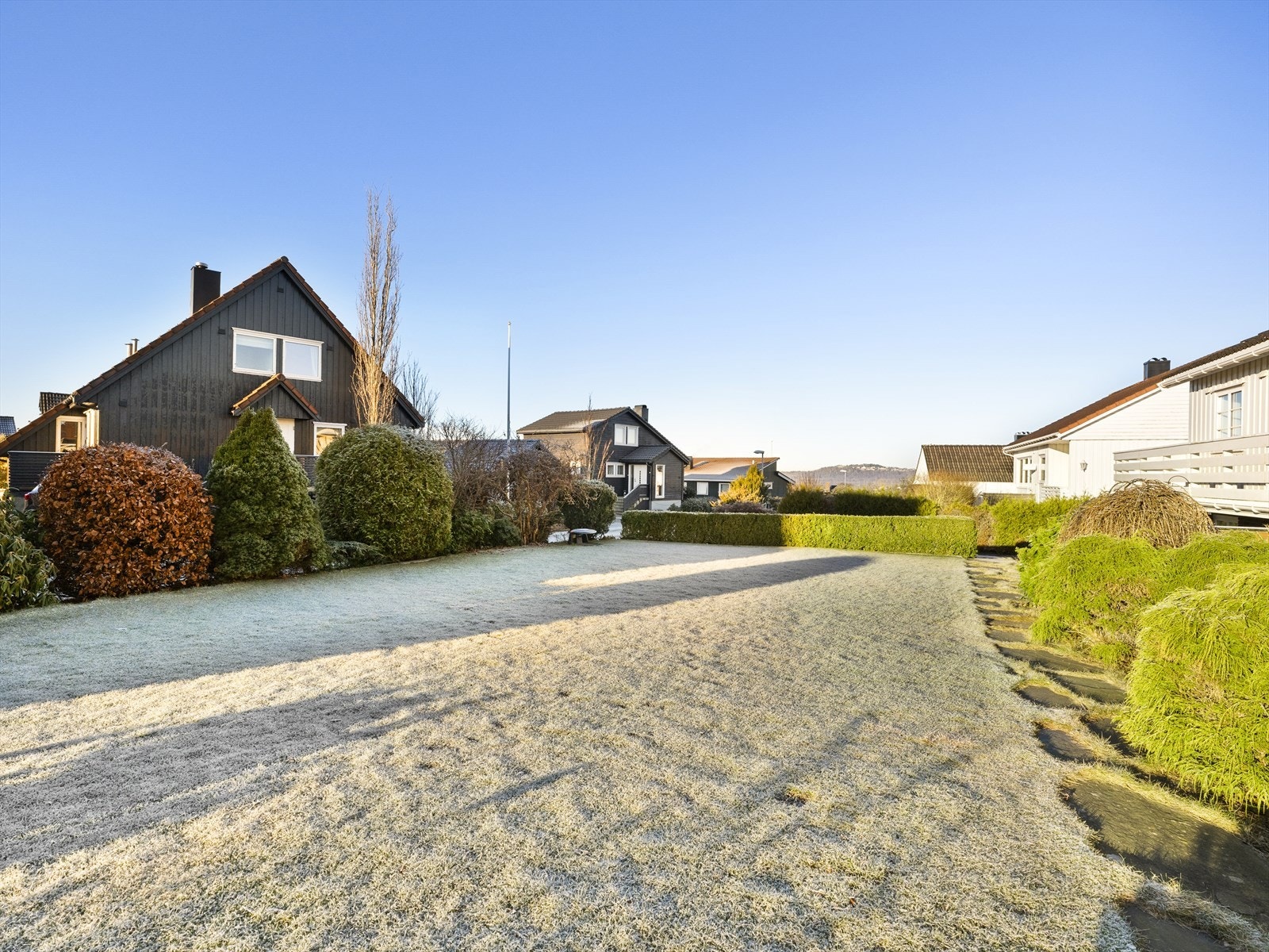 Pent opparbeidet med stor plen, busker, hekk og trær. Galleribilde